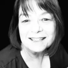 Black and white headshot of a woman who is smiling and has medium length straight hair with a wisp of bangs.