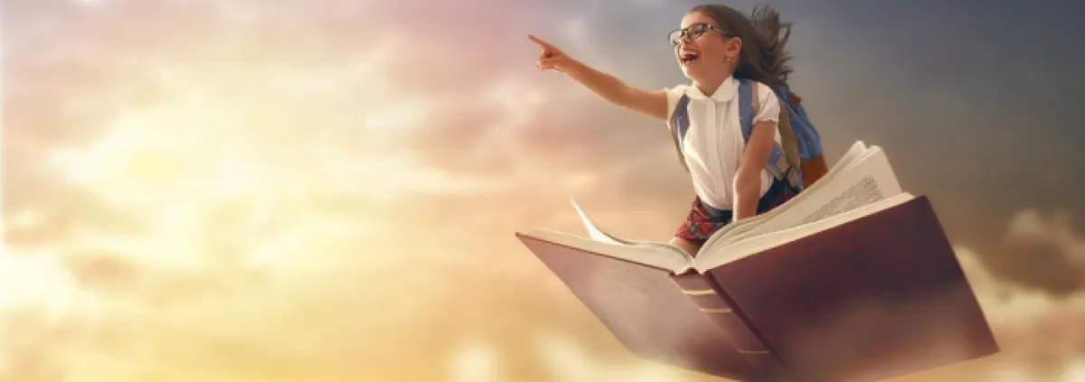 A child on top of a book flying to represent her imagination running free